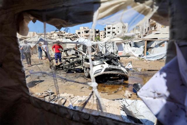 People gather around a destroyed vehicle following an Israeli strike in the Rimal neighbourhood of Gaza City on September 1, 2026. (Photo by Omar AL-QATTAA / AFP)