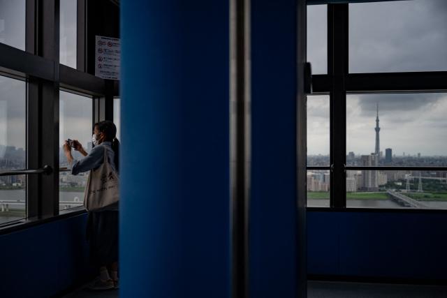A woman visits Tower Hall Funabori Observation Deck as the Tokyo Skytree (R) is seen in Edogawa district of Tokyo on September 1, 2026. (Photo by Philip FONG / AFP)