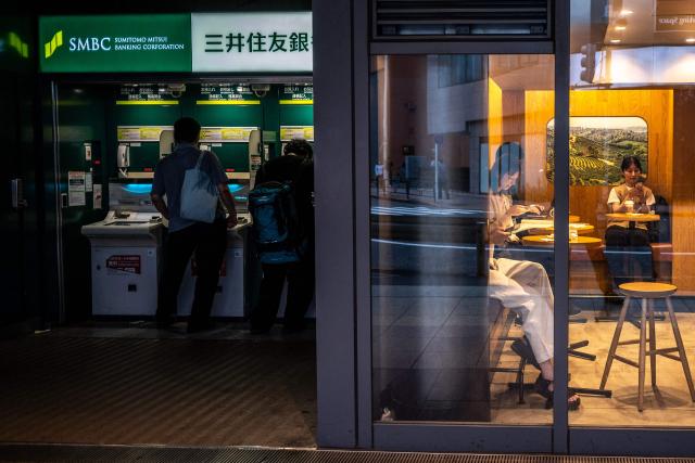 People sit in a cafe while others use an ATM at Shimbashi metro station in Tokyo on September 1, 2026. (Photo by Philip FONG / AFP)