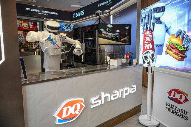 A Sharpa robot makes a Blizzard ice cream for a customer at a Dairy Queen store in Shanghai on September 1, 2026. (Photo by Jade GAO / AFP)