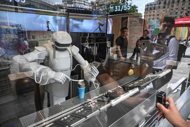 A Sharpa robot makes a Blizzard ice cream for a customer at a Dairy Queen store in Shanghai on September 1, 2026. (Photo by Jade GAO / AFP)