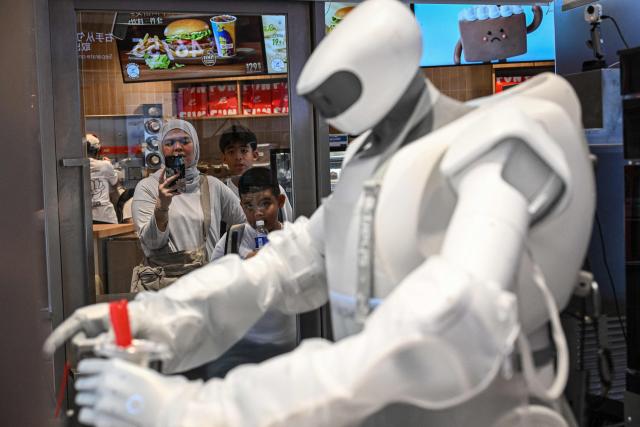 People watch a Sharpa robot making a Blizzard ice cream at a Dairy Queen store in Shanghai on September 1, 2026. (Photo by Jade GAO / AFP)