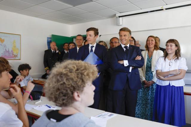 France's President Emmanuel Macron (Centre-R) reacts as he speaks with students flanked by France's Education Minister Edouard Geffray (Centre-L) during a visit of the Chaptal High School on the first day of the new academic year in Mende, southern France on September 1, 2026. Some 11.6 million primary, middle and secondary school pupils are returning to school on September 1, 2026, with headteachers' preparations having been disrupted by the fallout from a cyberattack targeting the French Ministry of Education this summer. Among the main changes this year are a ban on mobile phones in sixth-form colleges and the distribution to all pupils, from the final year of nursery school to the final year of sixth form, of a questionnaire on gender-based and sexual violence. (Photo by Guillaume HORCAJUELO / POOL / AFP)