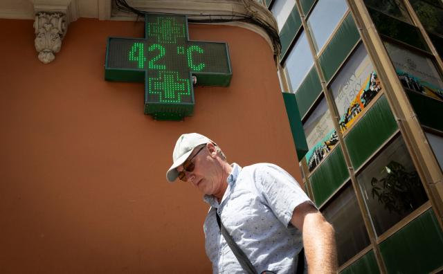 (FILES) A tourist walks past a sign that reads 42 degrees Celsius in Palma de Mallorca on June 20, 2026, on the eve of the start of the first official heatwave of this summer. Spain registered more than 5,000 heat-related deaths from June to August, data from a public health institute showed on August 31, 2026, a record since the start of its statistics in 2015. (Photo by Jaime REINA / AFP)