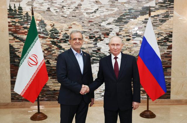 TOPSHOT - In this pool photograph distributed by the Russian state agency Sputnik, Russia's President Vladimir Putin and Iran's President Masoud Pezeshkian shake hands during a meeting on the sidelines of the Shanghai Cooperation Organisation (SCO) summit in Bishkek on September 1, 2026. (Photo by Vyacheslav PROKOFYEV / POOL / AFP)