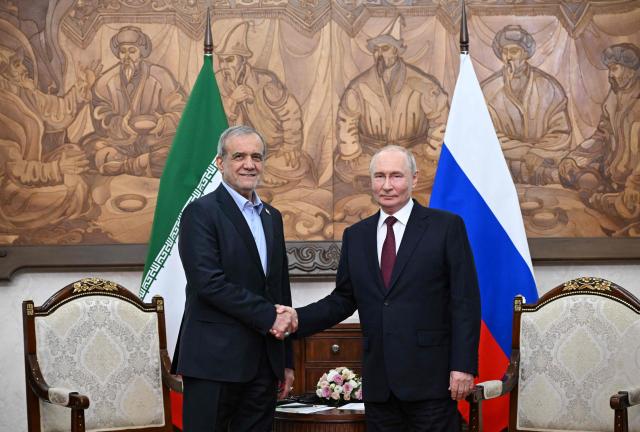 In this pool photograph distributed by the Russian state agency Sputnik, Russia's President Vladimir Putin and Iran's President Masoud Pezeshkian shake hands during a meeting on the sidelines of the Shanghai Cooperation Organisation (SCO) summit in Bishkek on September 1, 2026. (Photo by Kristina Solovyova / POOL / AFP)