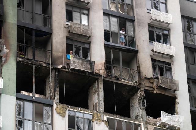 Residents stands on the balconies of their heavily damaged residential building following a Russian strike in Kyiv on September 1, 2026, amid the Russian invasion of Ukraine. Russia launched a barrage of drones and ballistic missiles at Kyiv and its surrounding region overnight, killing at least 12 people and wounding 21, Ukraine said on September 1, 2026, hitting the capital as children were set to return to school after the summer. (Photo by Vladyslav Musiienko / AFP)