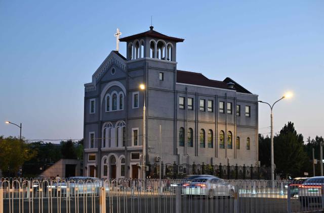 Motorists commute past a church in Beijing on September 1, 2026. (Photo by ADEK BERRY / AFP)