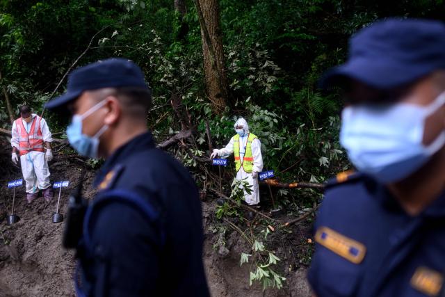 Security personnel watch as unidentified bodies of flood victims are prepared for mass burial at the Gokarna forest reserve in Kathmandu on September 1, 2026. The death toll from devastating Himalayan glacial floods crossed the grim 1,000 mark on September 1, as Chinese and Nepali teams searched for survivors including dozens feared trapped in hydropower tunnels. (Photo by MANAN VATSYAYANA / AFP)