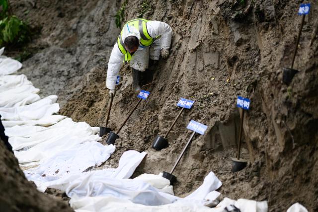 TOPSHOT - A security personnel puts number-tagged pots next to unidentified bodies of flood victims kept for mass burial at the Gokarna forest reserve in Kathmandu on September 1, 2026. The death toll from devastating Himalayan glacial floods crossed the grim 1,000 mark on September 1, as Chinese and Nepali teams searched for survivors including dozens feared trapped in hydropower tunnels. (Photo by MANAN VATSYAYANA / AFP)