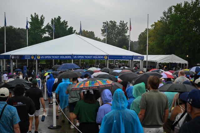 People stand in line to enter the US Open tennis tournament during a rainy day at the USTA Billie Jean King National Tennis Center in New York City on September 1, 2026. (Photo by ANGELA WEISS / AFP)