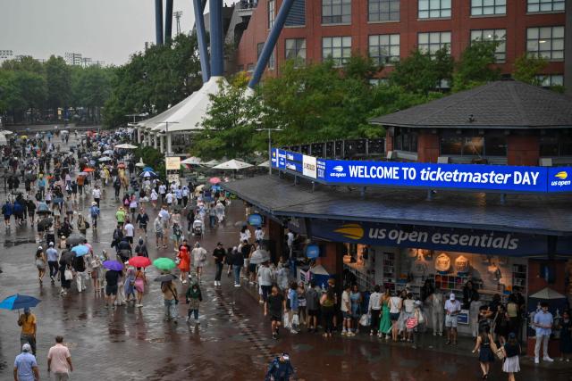 People walk through the rain during the US Open tennis tournament at the USTA Billie Jean King National Tennis Center in New York City on September 1, 2026. (Photo by ANGELA WEISS / AFP)