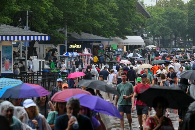 People walk through the rain during the US Open tennis tournament at the USTA Billie Jean King National Tennis Center in New York City on September 1, 2026. (Photo by ANGELA WEISS / AFP)