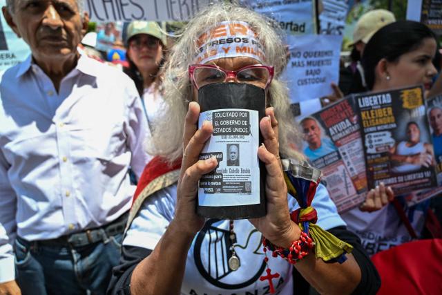 A relative of political prisoners holds a poster featuring Venezuelan Interior Minister Diosdado Cabello reading "Wanted by the US government" during the "How Much Oil Do Our Prisoners Cost?" march outside the Ministry of Prisons in Caracas on September 1, 2026. Relatives of political prisoners demonstrate in Caracas on September 1, calling on Washington over the failure to secure the release of their detained loved ones, as a major oil agreement between the United States and Venezuela takes shape. (Photo by Juan BARRETO / AFP)