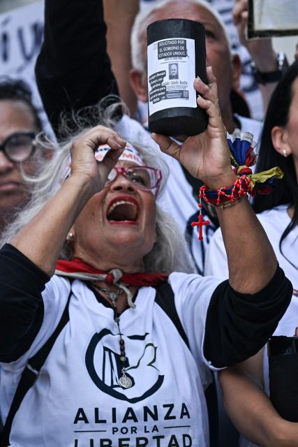 A relative of political prisoners holds a poster featuring Venezuelan Interior Minister Diosdado Cabello reading "Wanted by the US government" during the "How Much Oil Do Our Prisoners Cost?" march outside the Ministry of Prisons in Caracas on September 1, 2026. Relatives of political prisoners demonstrate in Caracas on September 1, calling on Washington over the failure to secure the release of their detained loved ones, as a major oil agreement between the United States and Venezuela takes shape. (Photo by Juan BARRETO / AFP)