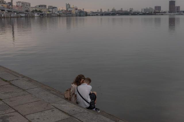 A young couple embrace as they sit by the Dnipro River during an air raid alert in Kyiv on September 1, 2026, amid the Russian invasion of Ukraine. (Photo by Roman PILIPEY / AFP)