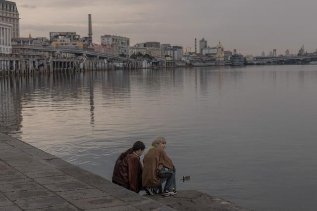 People sit by the Dnipro River during an air raid alert in Kyiv on September 1, 2026, amid the Russian invasion of Ukraine. (Photo by Roman PILIPEY / AFP)
