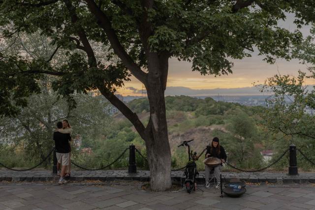 A couple embrace as a musician plays a handpan during an air raid alert in a park in Kyiv on September 1, 2026, amid the Russian invasion of Ukraine. (Photo by Roman PILIPEY / AFP)