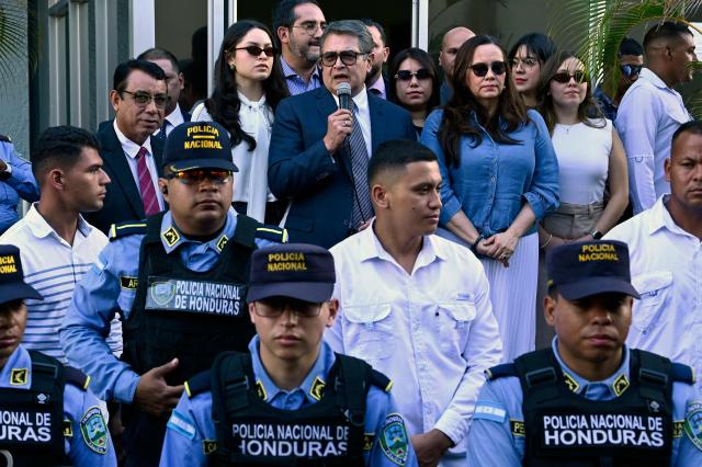 Former Honduran president Juan Orlando Hernandez (2014-2022) speaks to the press alongside his wife Ana Garcia (C, right) as police officers stand guard outside the Supreme Court of Justice in Tegucigalpa on September 1, 2026, after a judge dismissed corruption charges against him. Honduran justice on September 1 dismissed corruption charges against former president Juan Orlando Hernandez, who had previously been pardoned by US President Donald Trump following a drug trafficking conviction in the United States, the judiciary said. (Photo by Orlando SIERRA / AFP)
