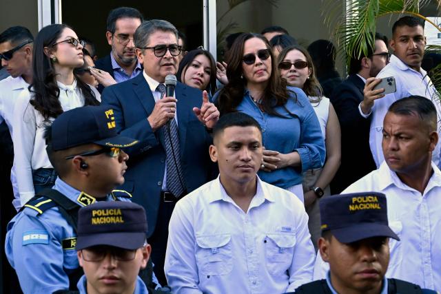Former Honduran president Juan Orlando Hernandez (2014-2022) speaks to the press alongside his wife Ana Garcia (C, right) as police officers stand guard outside the Supreme Court of Justice in Tegucigalpa on September 1, 2026, after a judge dismissed corruption charges against him. Honduran justice on September 1 dismissed corruption charges against former president Juan Orlando Hernandez, who had previously been pardoned by US President Donald Trump following a drug trafficking conviction in the United States, the judiciary said. (Photo by Orlando SIERRA / AFP)