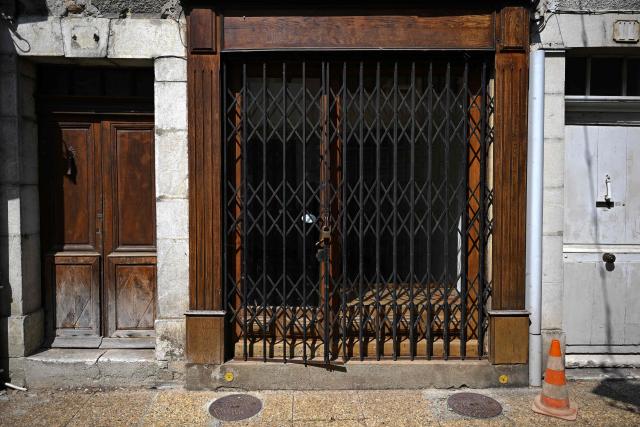 This photograph shows the storefront of a closed business in Saint-Gaudens, where commercial vacancy has increased over the past ten years on July 29, 2026. 'For sale', 'to let', 'potential to convert into a home': the streets of Saint-Gaudens' old town are dotted with closed-down commercial premises, whilst this town of just over 12,000 inhabitants at the foot of the Pyrenees fears losing its paper pulp mill and the hundreds of jobs it provides. "Watchmaker and jeweller", "quick alterations", "hairdresser", "optician"  these are the signs visible on some of the abandoned shop fronts, giving a clue as to what sort of business once occupied the premises. In other cases, there is no trace left of the former business. Some shop windows are even completely covered by posters of all kinds, including some dating back several years, such as one calling for a protest against the 2023 pension reforms. (Photo by Lionel BONAVENTURE / AFP)