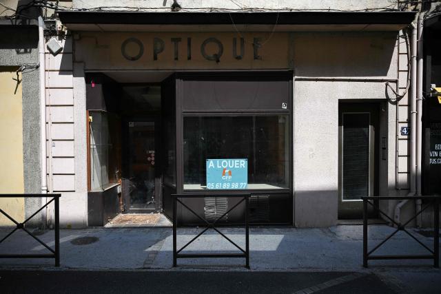This photograph shows the storefront of a closed business in Saint-Gaudens, where commercial vacancy has increased over the past ten years on July 29, 2026. 'For sale', 'to let', 'potential to convert into a home': the streets of Saint-Gaudens' old town are dotted with closed-down commercial premises, whilst this town of just over 12,000 inhabitants at the foot of the Pyrenees fears losing its paper pulp mill and the hundreds of jobs it provides. "Watchmaker and jeweller", "quick alterations", "hairdresser", "optician"  these are the signs visible on some of the abandoned shop fronts, giving a clue as to what sort of business once occupied the premises. In other cases, there is no trace left of the former business. Some shop windows are even completely covered by posters of all kinds, including some dating back several years, such as one calling for a protest against the 2023 pension reforms. (Photo by Lionel BONAVENTURE / AFP)