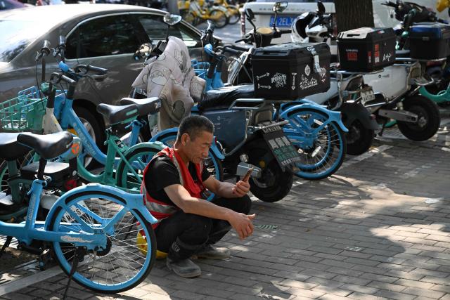 A construction worker checks his phone during a break in Beijing on September 2, 2026. (Photo by Pedro PARDO / AFP)