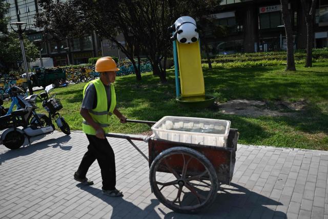 A construction worker pushes a wheelbarrow in Beijing on September 2, 2026. (Photo by Pedro PARDO / AFP)