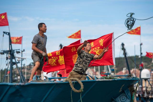 Fishermen work on their fishing boats at Jimiya Fishing Port in Qingdao West Coast New Area, in eastern China's Shandong province, on September 1, 2026, as the autumn fishing season begins following a four-month summer moratorium. (Photo by CN-STR / AFP) / China OUT