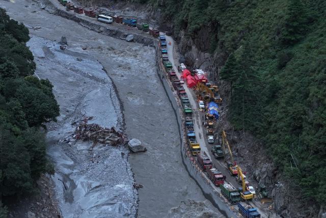 This aerial photo shows trucks and excavators during work to rebuild the road which leads to the destroyed Gyirong Port in Gyirong County, in China’s western Tibet region on September 1, 2026. The first batch of emergency machinery, including excavators, arrived at the search-and-rescue zone at the site of Gyirong Port on September 1. (Photo by CNS / AFP) / China OUT