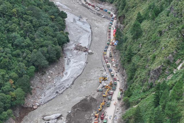 This aerial photo shows trucks and excavators during work to rebuild the road which leads to the destroyed Gyirong Port in Gyirong County, in China’s western Tibet region on September 1, 2026. The first batch of emergency machinery, including excavators, arrived at the search-and-rescue zone at the site of Gyirong Port on September 1. (Photo by CNS / AFP) / China OUT
