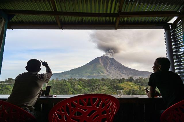 Two men watch Mount Sinabung spew ash and thick smoke as seen from Karo, North Sumatra province early on September 2, 2026. (Photo by Yt HARYONO / AFP)
