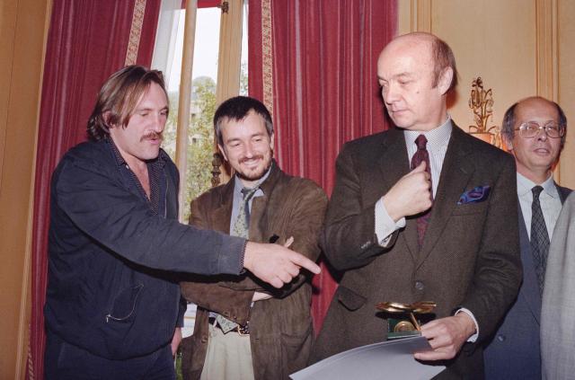 (FILES) French actor Gérard Depardieu (L) and director Jean-Jacques Beineix congratulate director Jean-Paul Rappeneau (R) who has awarded the Georges de Beauregard 1990 prize which rewards the best French production of the year for "Cyrano de Bergerac" in Paris on October 24, 1990. French filmmaker Jean-Paul Rappeneau, the multi-César-winning director of eight feature films, including "Cyrano de Bergerac" (1990), died in Paris on September 1, 2026 at the age of 94, one of his sons announced to AFP on September 2, 2026. (Photo by Gilles LEIMDORFER / AFP)