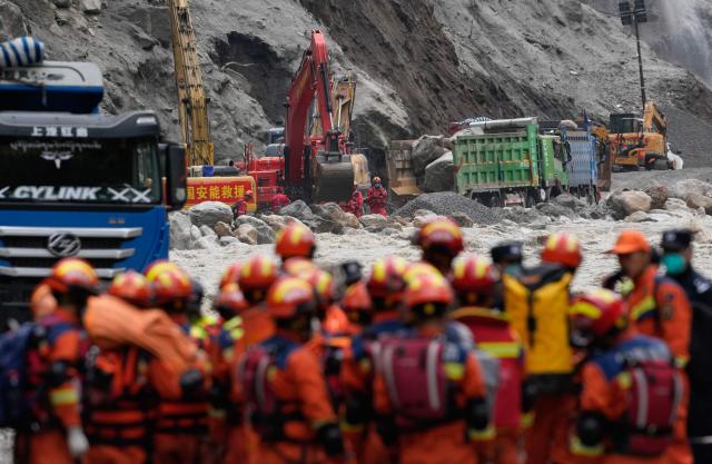 Chinese rescue personnel carrying supplies and equipment enter the core disaster area through a newly opened land route as excavators work at the destroyed Gyirong Port, in Gyirong County, in China's western Tibet Autonomous Region, on September 2, 2026. (Photo by CNS / AFP) / China OUT