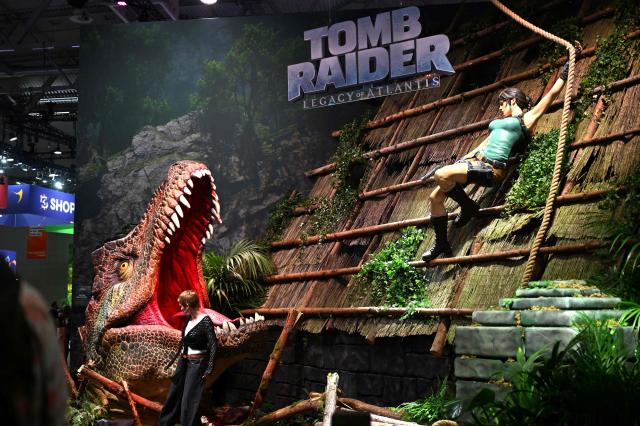 (FILES) A visitor poses at the "Tomb Raider: Legacy of Atlantis" video game of Crystal Dynamics and Flying Wild Hogduring at the Gamescom video games trade fair on the fair grounds in Cologne, western Germany, on August 26, 2026. Thirty years after bursting onto the video game scene, Lara Croft returns in a new "Tomb Raider" that plays up the pistol-wielding architect's "complicated" character. Taking on the most famous heroine in video game history is a "tremendous responsibility", Raul Siqueira, director of "Tomb Raider: Legacy of Atlantis", told AFP in an interview at the Gamescom video game convention in Cologne, Germany. (Photo by Ina FASSBENDER / AFP)