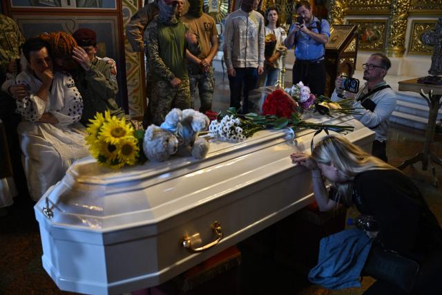 Relatives and friends mourn during the funeral service of the late paramedic of the Ukrainian volunteer medical battalion Hospitallers, Eva Roiter, 25, in Saint Michael's Golden-Domed Cathedral in Kyiv on September 2, 2026, amid the Russian invasion of Ukraine. (Photo by Genya SAVILOV / AFP)