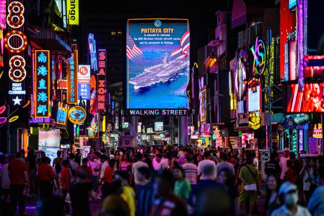 Pedestrians walk past a LED display welcoming the arrival of US service personnel of the nuclear-powered aircraft carrier USS Abraham Lincoln (CVN-72) in Pattaya on September 2, 2026. (Photo by ANTHONY WALLACE / AFP)