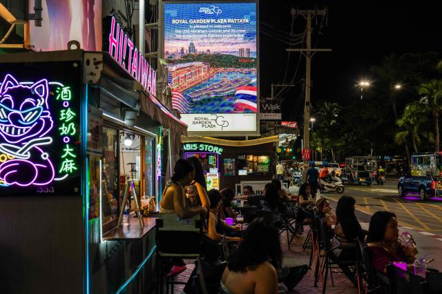 People sit near a large LED screen Top C) welcoming the arrival of US service personnel of the nuclear-powered aircraft carrier USS Abraham Lincoln (CVN-72) in Pattaya on September 2, 2026. (Photo by ANTHONY WALLACE / AFP)
