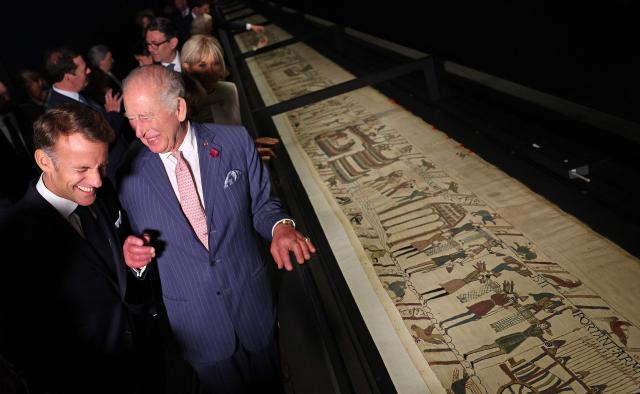 Britain's King Charles III and France's President Emmanuel Macron, accompanied by their wives Britain's Queen Camilla and Brigitte Macron (obscured) view sections of the Bayeux Tapestry during a preview event for the Bayeux Tapestry Exhibition, at the British Museum in London on September 2, 2026. (Photo by Adrian Dennis / POOL / AFP)