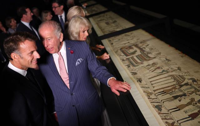 Britain's King Charles III and France's President Emmanuel Macron, accompanied by their wives Britain's Queen Camilla and Brigitte Macron (obscured) view sections of the Bayeux Tapestry during a preview event for the Bayeux Tapestry Exhibition, at the British Museum in London on September 2, 2026. (Photo by Adrian Dennis / POOL / AFP)
