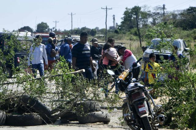People walk and ride motorcycles past a road blockade set up by agricultural producers in the town of Cuatro Canadas, Santa Cruz department, Bolivia, on September 2, 2026, in protest against Supreme Decree 5676, which raises the price of diesel. (Photo by RODRIGO URZAGASTI / AFP)
