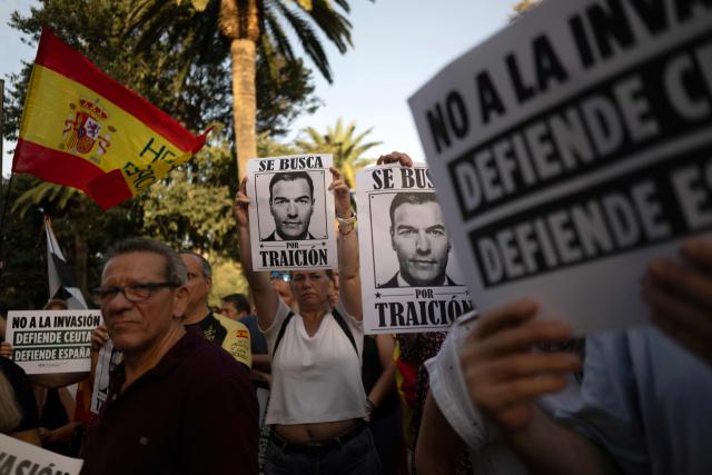 Protesters hold a banners mocking Spain's Prime Minister Pedro Sanchez reading 'wanted for treason' during a demonstration one month after a mass influx of migrants in Ceuta, in Malaga, on September 2, 2026. Local anger divide Ceuta one month after the mass influx of migrants into the North African Spanish territory. 5,000 migrants according to the government, or at least 10,000, according to Ceuta authorities, remain in the small territory of 18.5 square kilometers and 80,000 inhabitants, wandering the streets in search of food and sleeping in streets and on beaches. (Photo by JORGE GUERRERO / AFP)