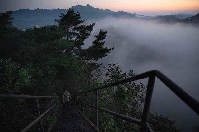 A hiker descends from the summit of Inwangsan Mountain in Seoul on September 3, 2026. (Photo by Lillian SUWANRUMPHA / AFP)