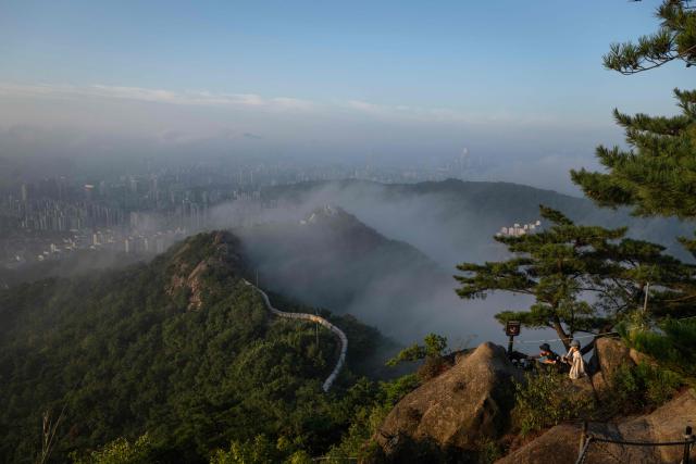 Hikers enjoy the view of the skyline and Seoul City Wall on Inwangsan Mountain in Seoul on September 3, 2026. (Photo by Lillian SUWANRUMPHA / AFP)