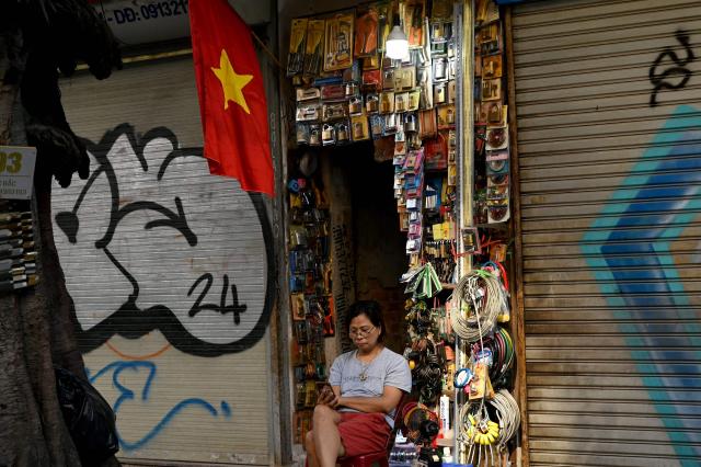 A woman sits using her phone in front of a lock shop in Hanoi on September 3, 2026. (Photo by Nhac NGUYEN / AFP)