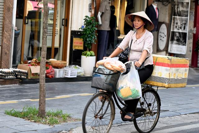 A "banh mi" street vendor cycles along a street in Hanoi on September 3, 2026. (Photo by Nhac NGUYEN / AFP)