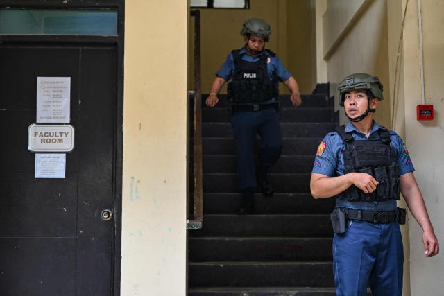 Policemen walk around during a nationwide school drills to safeguard students from armed intruders, at a school in San Rafael, Bulacan on September 3, 2026. The drills came following a student livestreaming himself shooting another schoolmate dead before taking his own life at a high school in the Philippines on August 18, authorities said. (Photo by Jam STA ROSA / AFP)