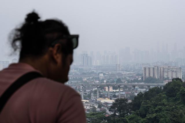 A man stands as haze shrouds the Kuala Lumpur skyline, as seen from Ampang, in Malaysia’s Selangor state, on September 3, 2026. Indonesia has for weeks battled wildfires that have led to school closures and thousands of people requiring medical treatment, with smoke also drifting across to Malaysia and Singapore. (Photo by Mohd Rasfan / AFP)