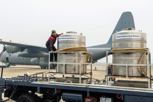 A man prepares cloud-seeding tanks before they are loaded onto a Royal Malaysian Air Force C-130 aircraft at the air force base in Kuching, the capital of Sarawak state on the island of Borneo, on September 3, 2026. Malaysia launched a three-day cloud-seeding operation on September 3 in a bid to ease hazardous haze choking Sarawak state, as smoke from Indonesian forest fires pushed air quality to dangerous levels. (Photo by AFP) / Malaysia OUT