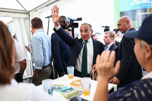 French far-right Reconquete! party leader Eric Zemmour (C) waves to attendees as he visits the agricultural fair in Chalons-en-Champagne, northeastern France on September 3, 2026. (Photo by Sameer AL-DOUMY / AFP)